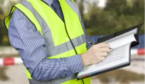 Building surveyor in hi vis checking data on building site (2)
